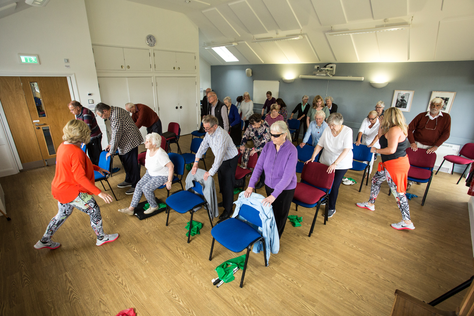 Exercise class with eldery clients smiling and standing in a classroom