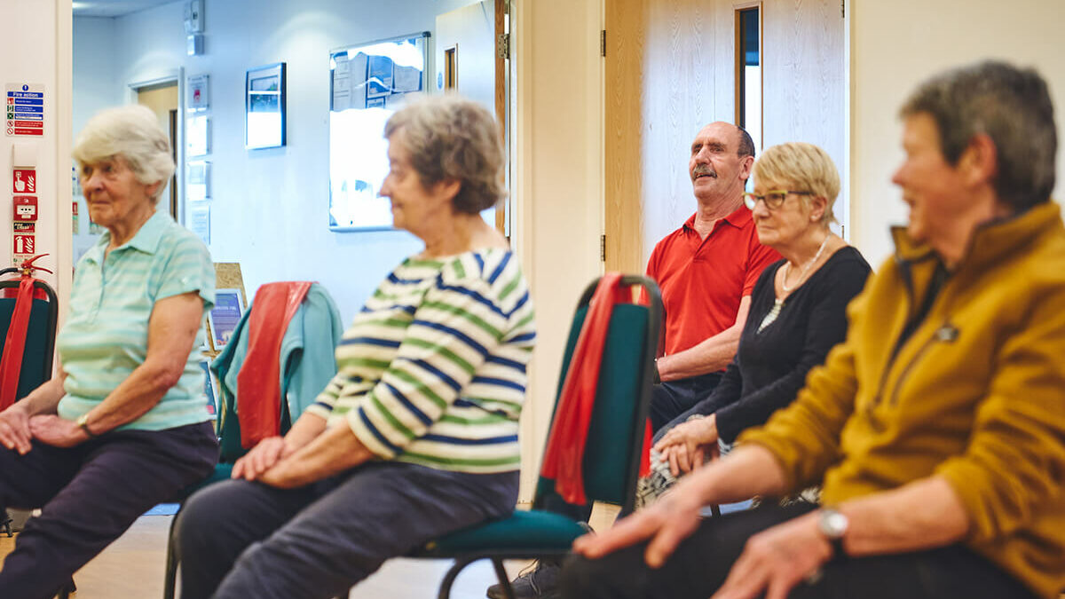 A group of older people at a falls prevention and mobility class with happy faces.