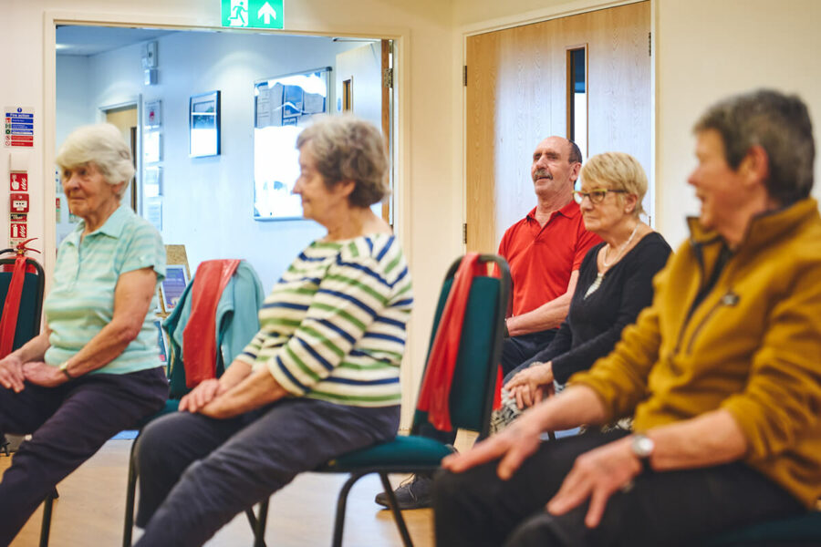 A group of older people at a falls prevention and mobility class with happy faces.