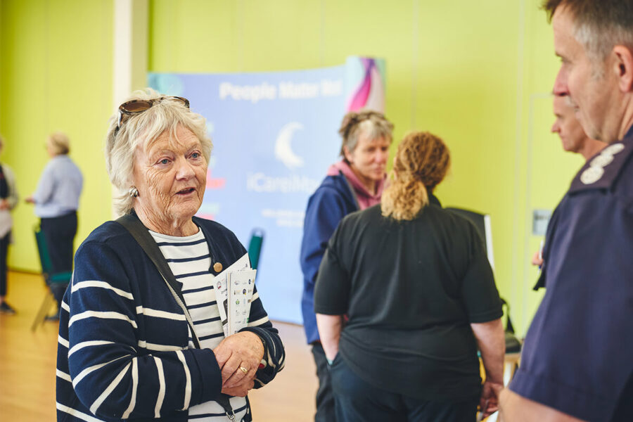 An older lady speaking to a Firefighter at a Triservice healthcare event.