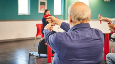 Older man at an iCareiMove Impact falls Prevention Event doing grip and hand exercises with resistance bands