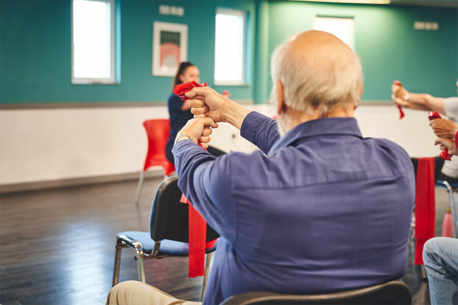 Older man at an iCareiMove Impact falls Prevention Event doing grip and hand exercises with resistance bands