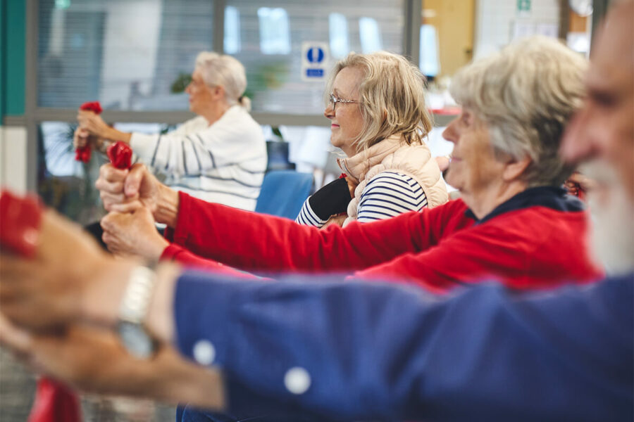 Older participants at an iCareiMove Impact falls Prevention Event doing grip and hand exercises with resistance bands