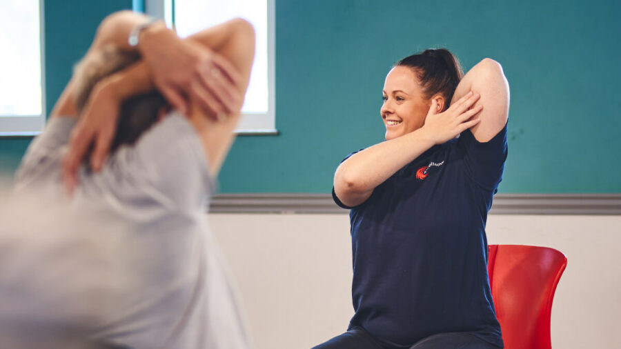 An iCareiMove Instructor leads gentle seated exercise activities at an Impact falls prevention event.