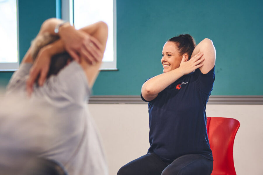 An iCareiMove Instructor leads gentle seated exercise activities at an Impact falls prevention event.