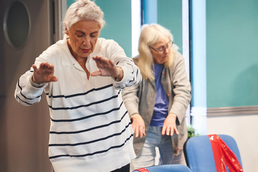 Two older women doing group falls prevention exercise activities at an iCareiMove Impact Event.