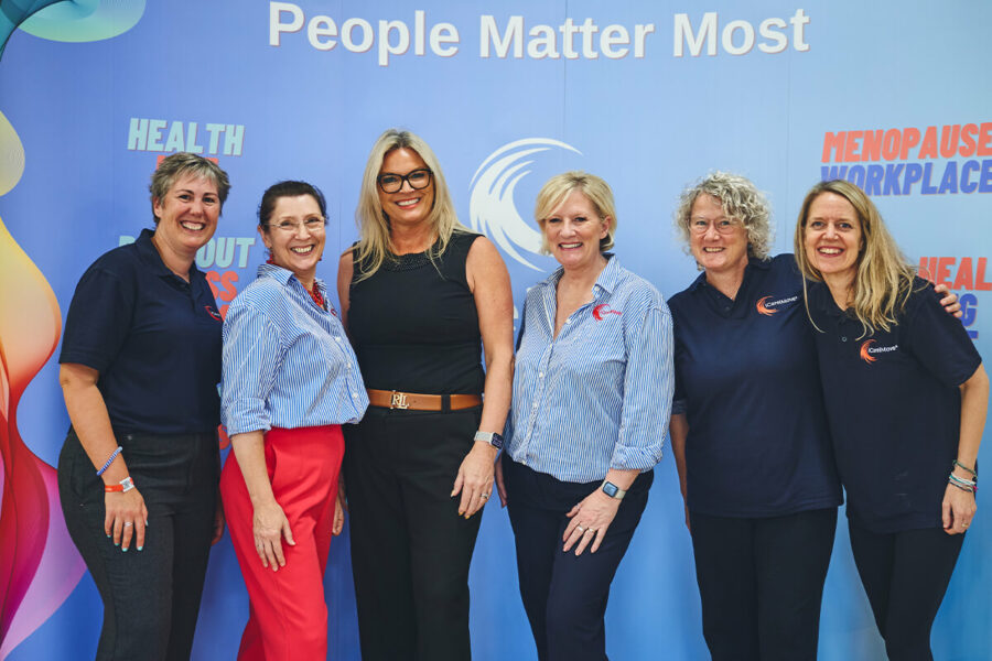 iCareiMove management and instructor team pose in front of a healthcare event banner.